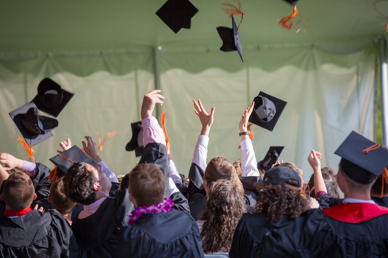 creative-03 Group of graduates celebrating by tossing caps into the air during a graduation ceremony.