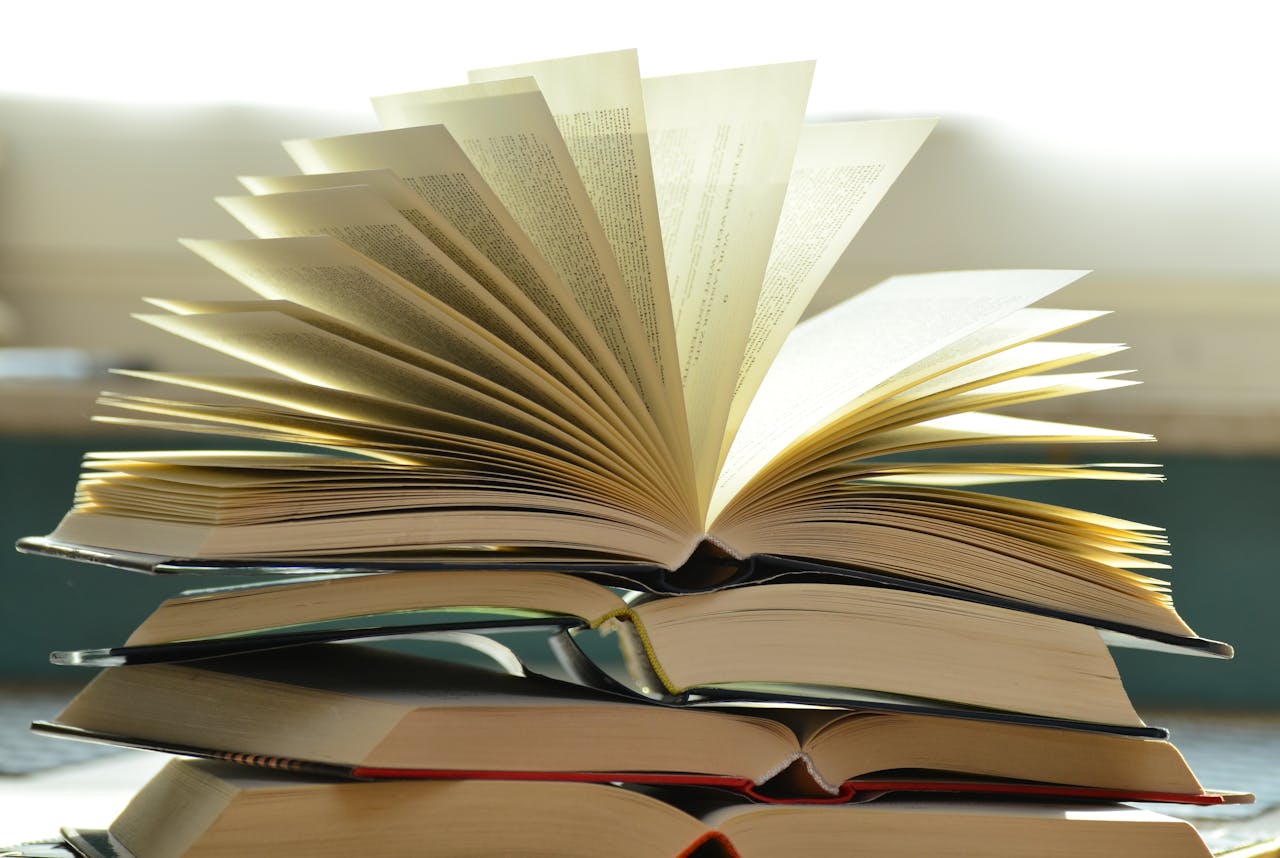 Services-02 A close-up of a stack of open books with pages fanned out, capturing a study atmosphere.